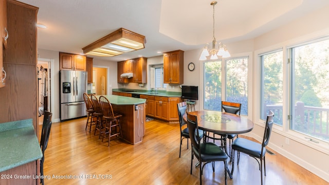 dining space with sink, an inviting chandelier, and light hardwood / wood-style flooring