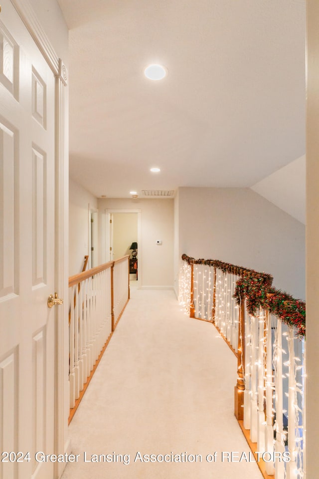 hall with carpet floors and vaulted ceiling