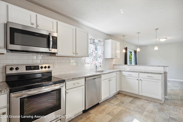 kitchen featuring kitchen peninsula, white cabinets, pendant lighting, and appliances with stainless steel finishes