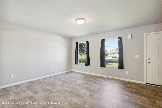 spare room featuring wood-type flooring and a textured ceiling