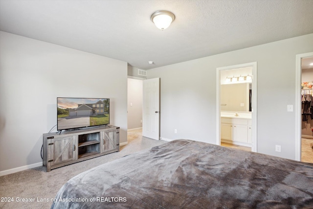 carpeted bedroom with connected bathroom, sink, and a textured ceiling