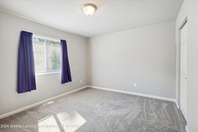 carpeted empty room featuring a textured ceiling