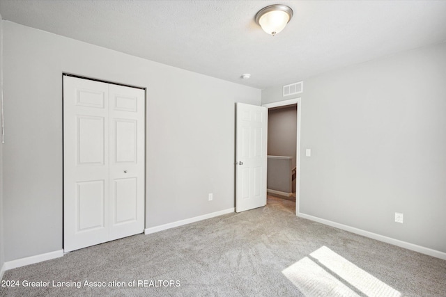 unfurnished bedroom featuring light colored carpet and a closet