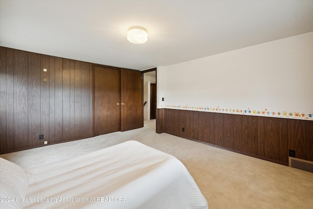 bedroom featuring light colored carpet and wood walls