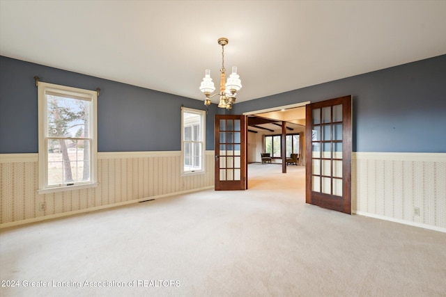 unfurnished room featuring an inviting chandelier, french doors, and carpet flooring