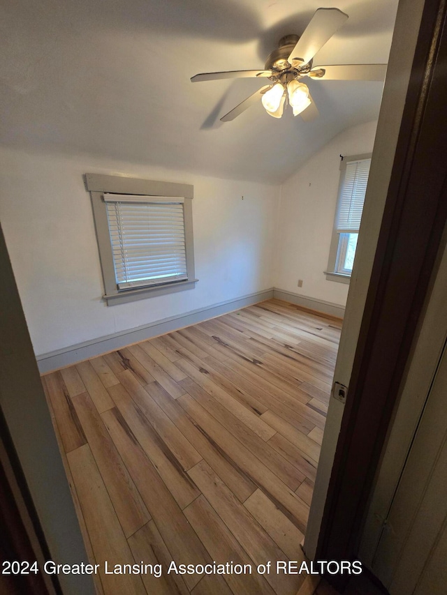 unfurnished room with ceiling fan, vaulted ceiling, and light wood-type flooring