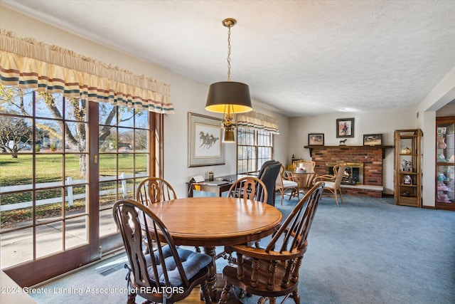 carpeted dining room featuring a brick fireplace and a textured ceiling