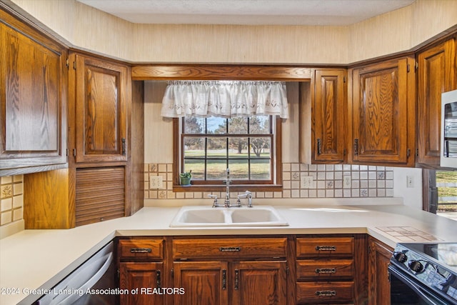 kitchen featuring a healthy amount of sunlight, decorative backsplash, sink, and dishwasher