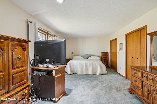 bedroom featuring light colored carpet and a textured ceiling