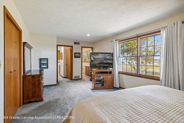 bedroom with a textured ceiling and light colored carpet