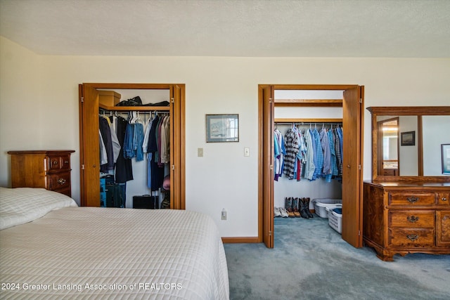 carpeted bedroom featuring a textured ceiling and two closets