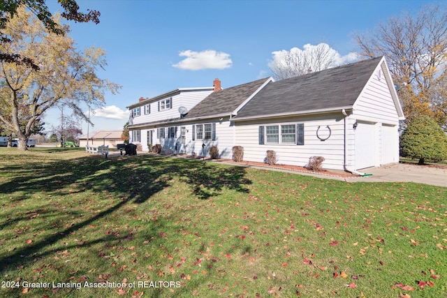 rear view of house with a garage and a yard