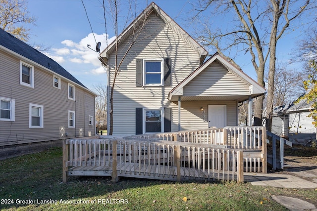 back of property with a lawn and a wooden deck