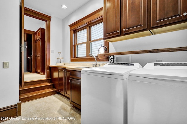 laundry room featuring washing machine and clothes dryer, sink, cabinets, and light wood-type flooring