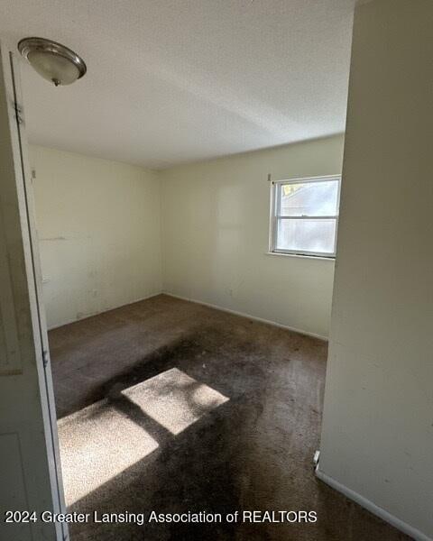 spare room featuring dark colored carpet