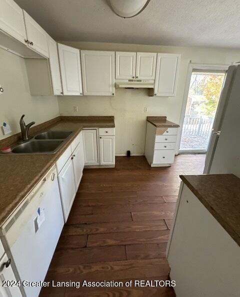 kitchen with white dishwasher, white cabinets, a textured ceiling, sink, and dark hardwood / wood-style floors