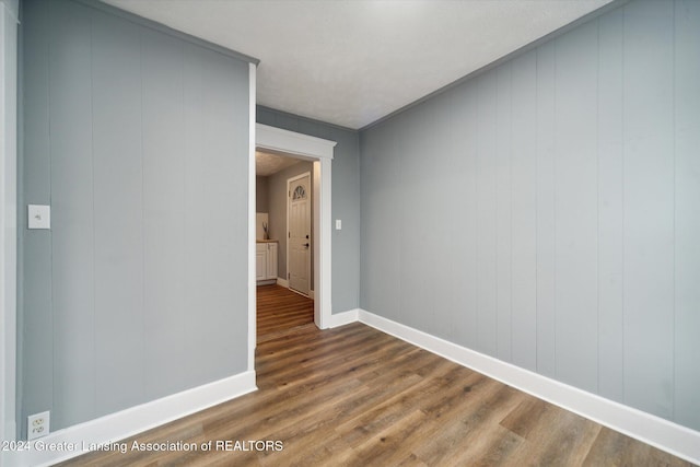 spare room featuring hardwood / wood-style floors, wood walls, and ornamental molding