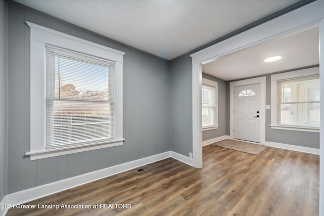 entrance foyer with a wealth of natural light, dark wood-type flooring, and crown molding