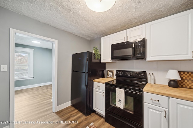 kitchen with black appliances, light wood-type flooring, white cabinets, and wood counters