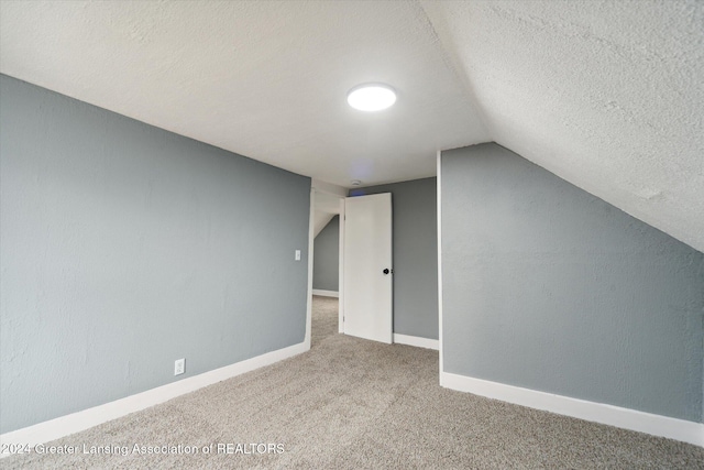 additional living space with a textured ceiling, carpet flooring, and lofted ceiling