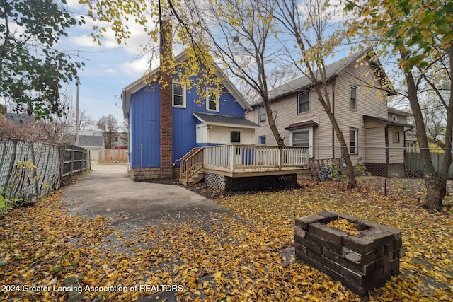 back of property with a fire pit and a deck