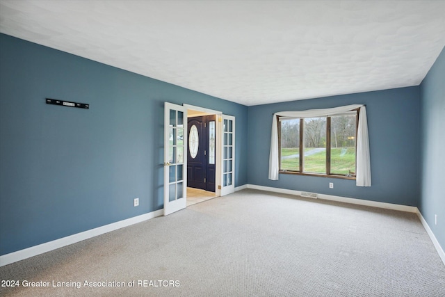 spare room featuring light colored carpet and french doors