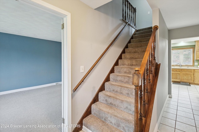 stairs with tile patterned flooring and sink