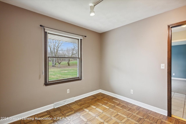 unfurnished room with light parquet floors and track lighting