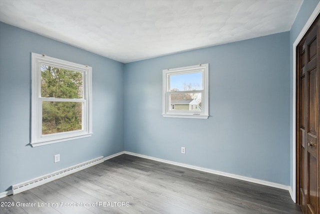 empty room featuring a baseboard heating unit and hardwood / wood-style flooring