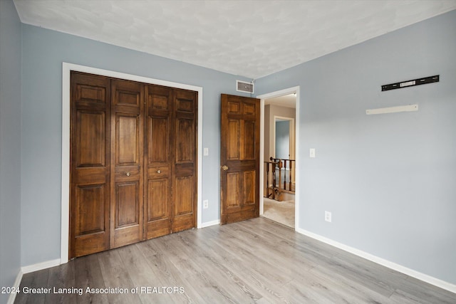 unfurnished bedroom with light hardwood / wood-style flooring and a closet