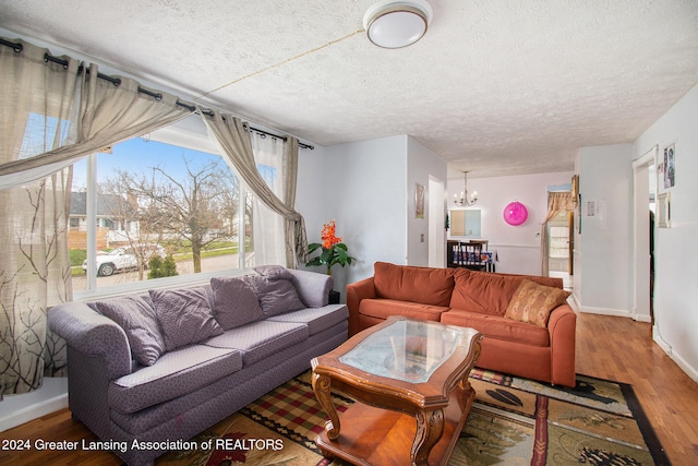 living room featuring a textured ceiling, hardwood / wood-style flooring, and a notable chandelier