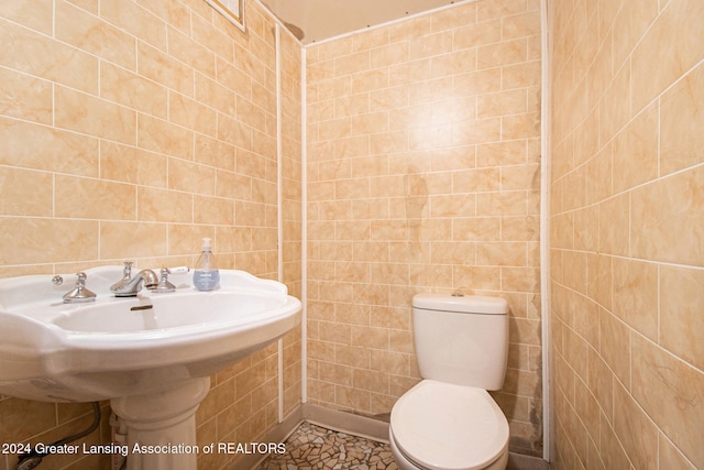 bathroom featuring sink, tile patterned flooring, toilet, and tile walls