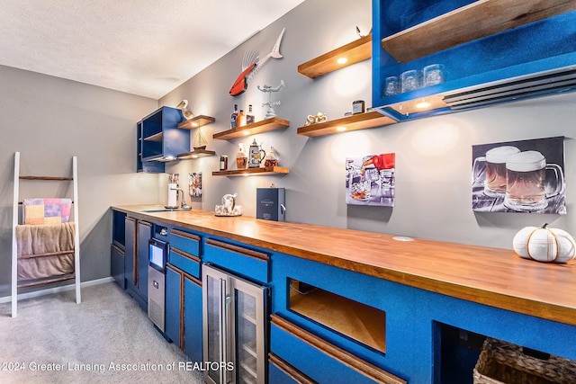 bar featuring butcher block counters, wine cooler, sink, blue cabinets, and light colored carpet