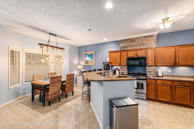 kitchen with a textured ceiling, a breakfast bar area, an island with sink, stainless steel gas range, and pendant lighting