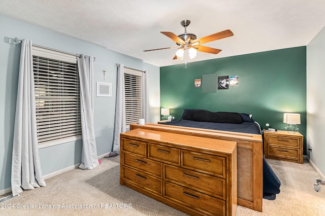 bedroom featuring a textured ceiling, light carpet, and ceiling fan