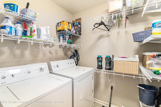 laundry area with washing machine and clothes dryer and a textured ceiling