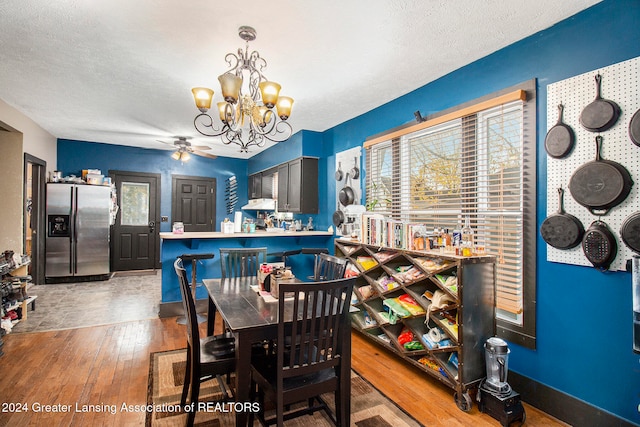 dining space featuring a textured ceiling, ceiling fan with notable chandelier, and dark hardwood / wood-style floors