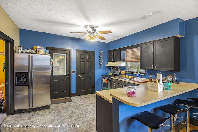 223 S Pennsylvania Ave, Lansing, MI 48912 - kitchen featuring stainless steel appliances, under cabinet range hood, a sink, ceiling fan, and a breakfast bar