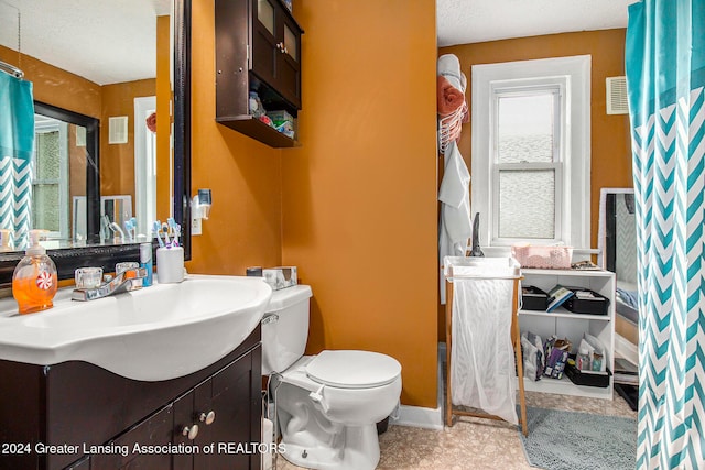 bathroom with vanity, toilet, and a textured ceiling