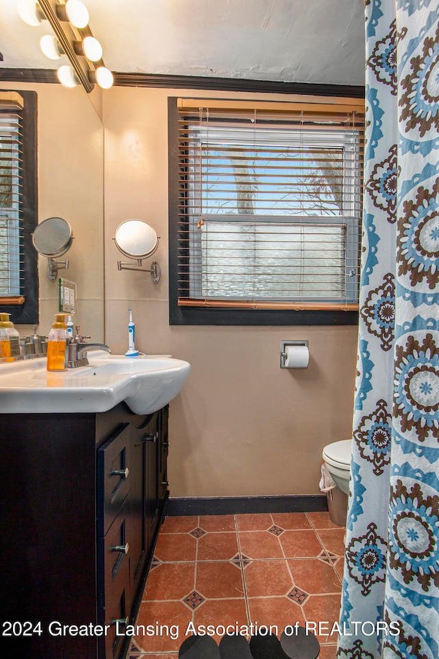 bathroom featuring tile patterned floors, crown molding, vanity, and toilet