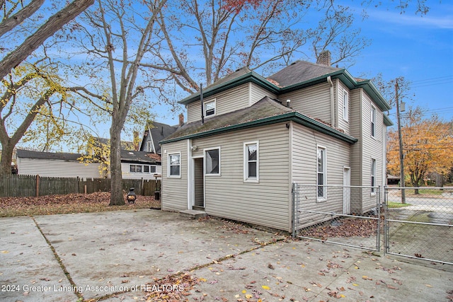 223 S Pennsylvania Ave, Lansing, MI 48912 - back of property with a patio area, a chimney, fence, and a gate