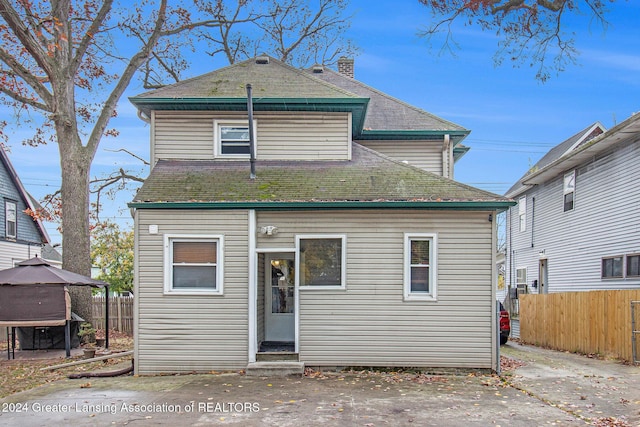 223 S Pennsylvania Ave, Lansing, MI 48912 - back of house with entry steps, a gazebo, fence, a chimney, and a shingled roof