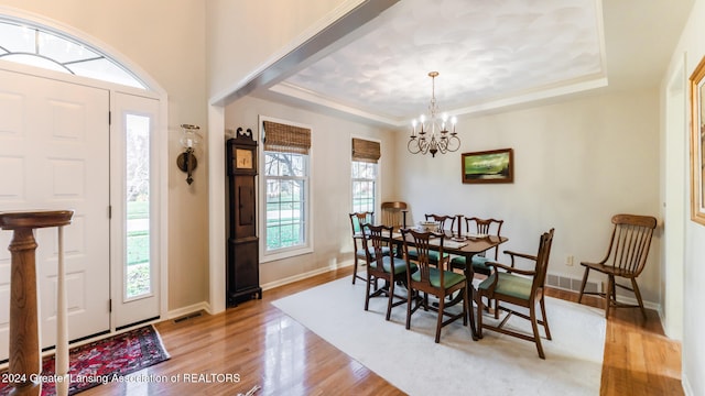 dining area featuring light hardwood / wood-style flooring, a chandelier, and a raised ceiling