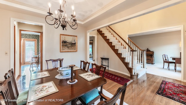 dining area featuring an inviting chandelier, light wood-type flooring, crown molding, and a tray ceiling