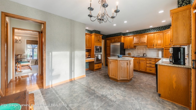 kitchen featuring appliances with stainless steel finishes, backsplash, a notable chandelier, a center island, and pendant lighting