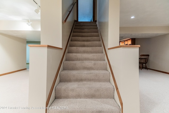 stairs with carpet flooring and track lighting