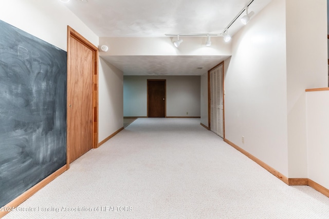 hallway featuring track lighting and light carpet