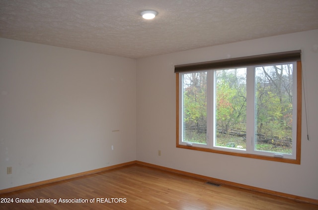 spare room with light hardwood / wood-style floors and a textured ceiling