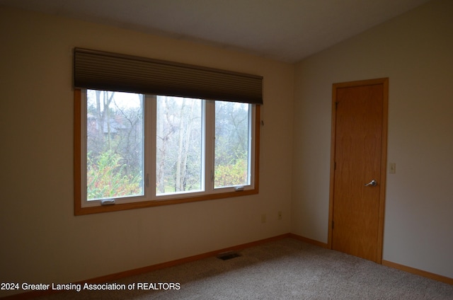 unfurnished room with plenty of natural light, lofted ceiling, and carpet floors