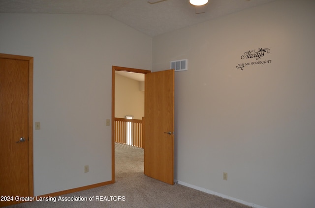 spare room with light colored carpet, vaulted ceiling, and ceiling fan